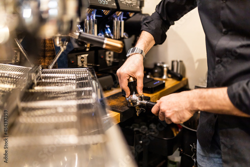 unrecognizable barista making espresso coffee in his coffee machine in a coffee shop