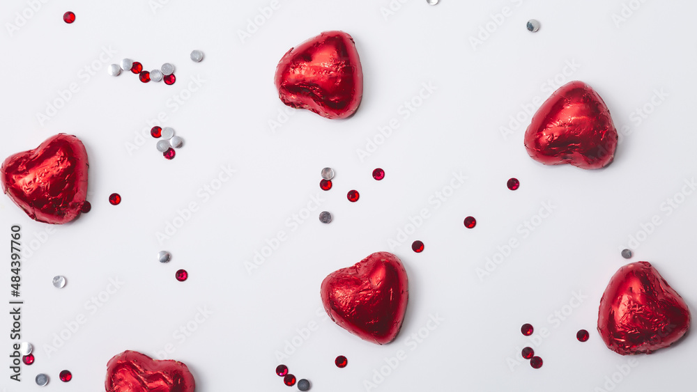 Fototapeta premium Red foiled chocolate hearts on a white background, chocolate hearts. Valentines day concept