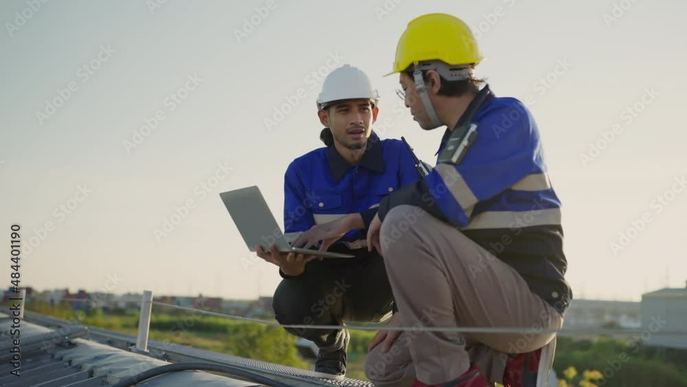 Specialist technician professional engineer with laptop and tablet maintenance checking installing solar roof panel on the factory rooftop under sunlight. Engineers team survey check solar panel roof. Specialist technician professional engineer with laptop and tablet maintenance checking installing solar roof panel on the factory rooftop under sunlight. Engineers team survey check solar panel roof.