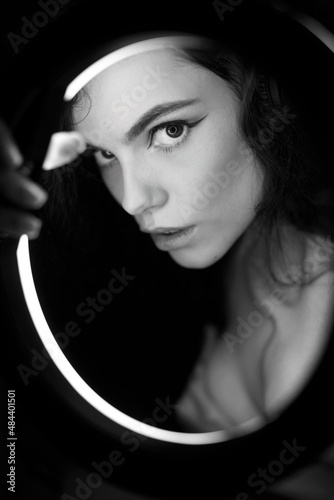 Emotional studio portrait of a young woman in a wireless headphones with ring flash effect. Round LED Circle Lamp.