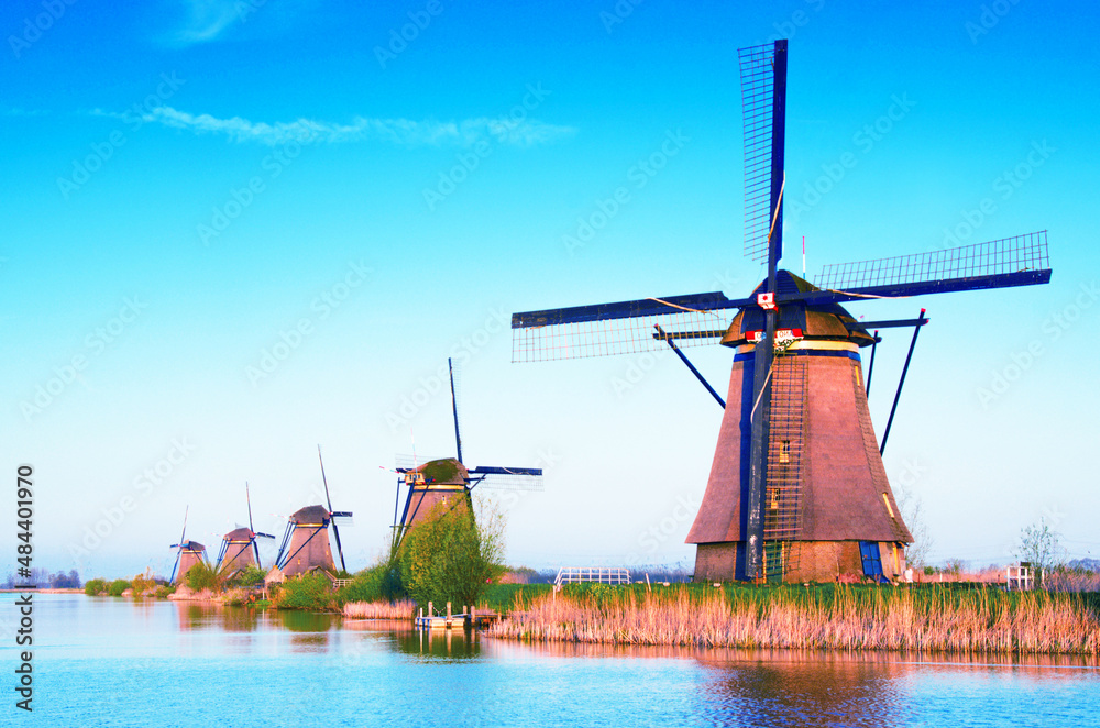 The charming landscape with windmills in Kinderdijk, Netherlands, Europe against a background of cloudy sky reflection in the water.