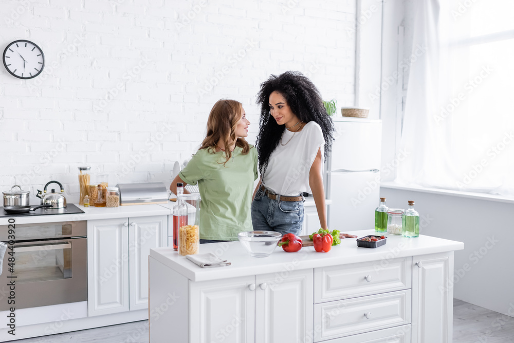 happy multiethnic lesbian couple looking at each other in modern kitchen. happy multiethnic lesbian couple looking at each other in modern kitchen.