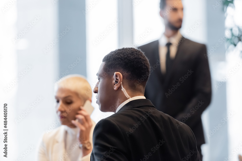 african american bodyguard near mature businesswoman talking on smartphone in hotel. african american bodyguard near mature businesswoman talking on smartphone in hotel.