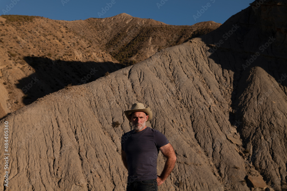 Adult man in cowboy hat on desert against mountain. Almeria, Spain Adult man in cowboy hat on desert against mountain. Almeria, Spain