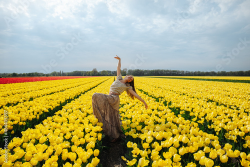 Dancing girl in a flower field full of yellow tulips in the Netherlands