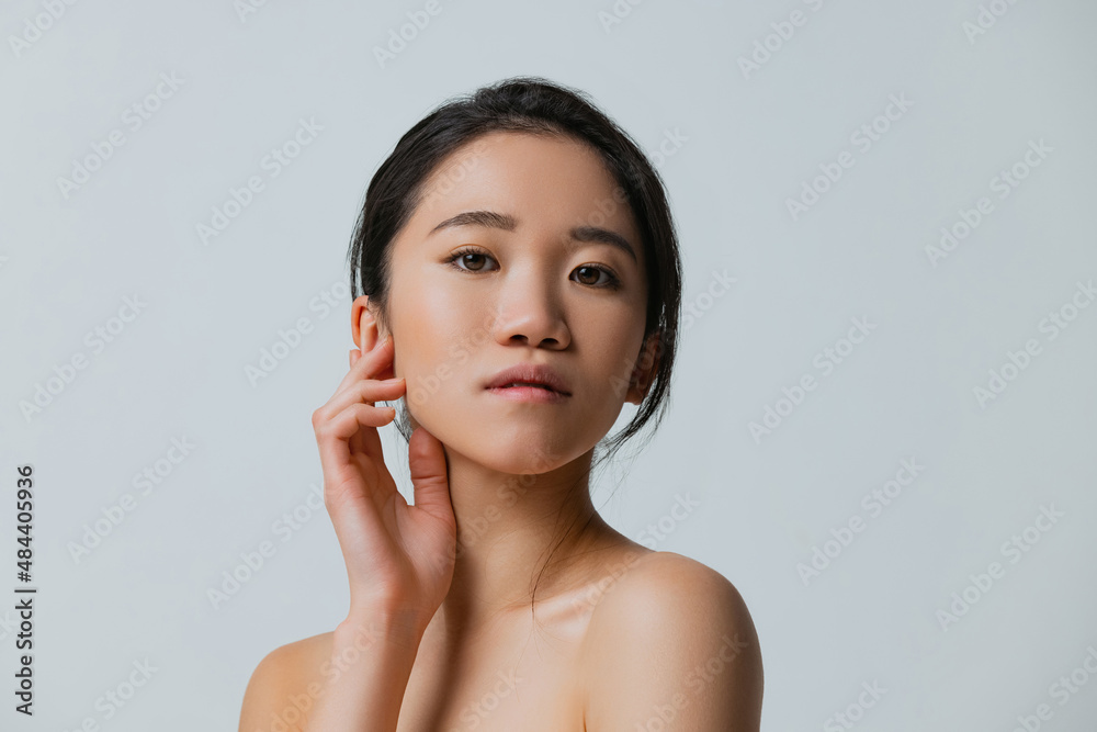 Half-length portrait of beautiful asian girl with natural makeup posing isolated over gray studio background Half-length portrait of beautiful asian girl with natural makeup posing isolated over gray studio background