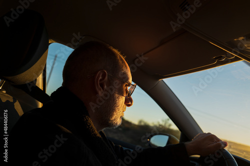 Headshot of adult man with sunglasses driving car.