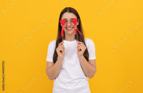 smiling girl hold heart in white shirt on yellow background, womens day