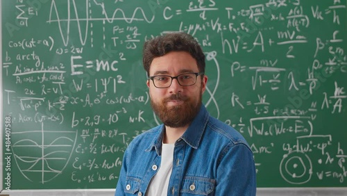 Portrait of happy young man student standing in class with arms crossed smiling looking at camera