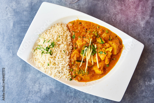 Leckeres indisches Essen mit Basmatireis und frischem Gemüse und Kräutern serviert in einem indischen Restaurant auf schönen weißen Tellern photo