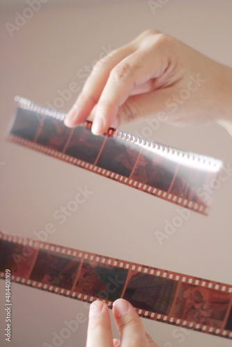 A woman's hand holding a 35 mm film and shining in the light outside the room.