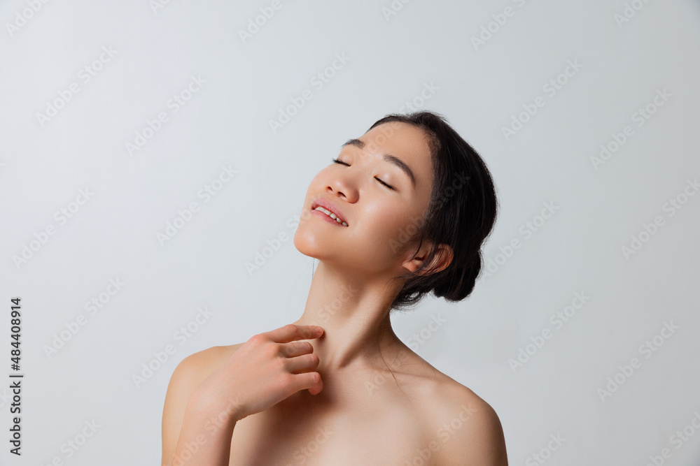 Cropped studio portrait of tender asian woman posing isolated over gray background Cropped studio portrait of tender asian woman posing isolated over gray background