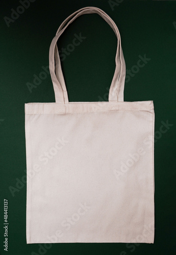  Mock-up eco friendly beige or white color canvas cotton fabric tote bag on dark green background. Shopping sack mockup blank template. Reusable bag for groceries and shopping.
