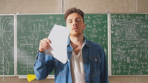 Young teacher fanning paper sheets in a very hot classroom