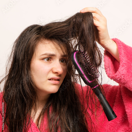 A woman with wet long tangled hair tries to comb photo