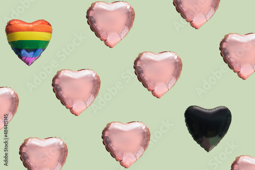 Pattern created of many pink heart shaped balloons, a rainbow color and a black balloon. Green pastel background. Diversity, LGBT liberation and black lives matters abstract concept. photo