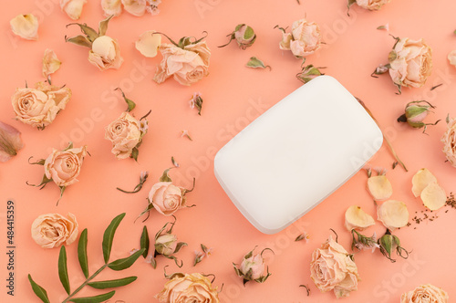 Top view of a bar of soap on a playful pink background with dried rose flowers. The concept of hygiene and skin care.