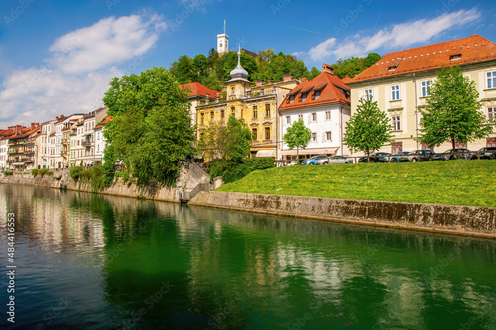 Embankment of Ljubljanica river and old buildings and castle tower in the historical center of Ljubljana, Slovenia