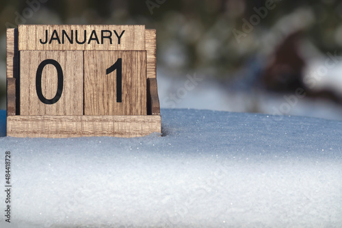 Wooden calendar of January 1 date standing in the snow in nature.
