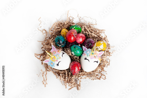 traditional Easter decoration. multicolored quail eggs and two white unicorn eggs in a nest on a white background. top