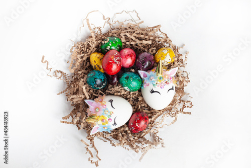 traditional Easter decoration. multicolored quail eggs and two unicorn eggs in a nest on a white background