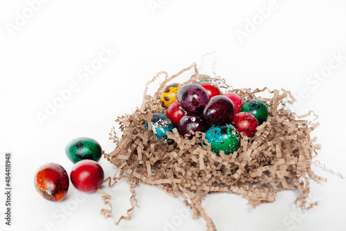 traditional Easter decoration. multicolored bright quail eggs in a nest on a white background.