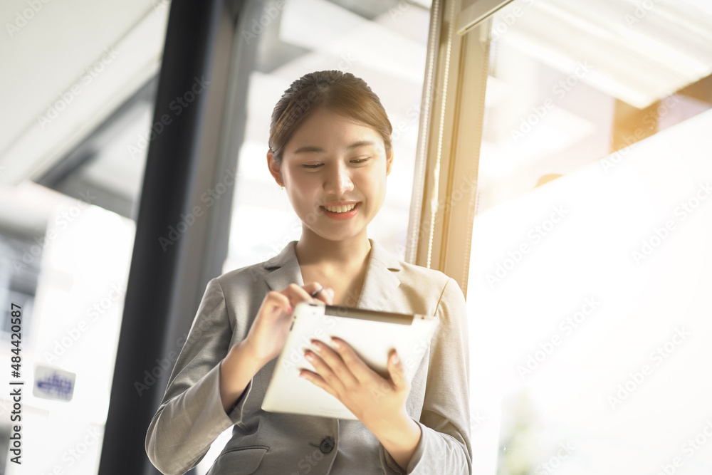 Young attractive Asian woman smile and looking to tablet on hands.