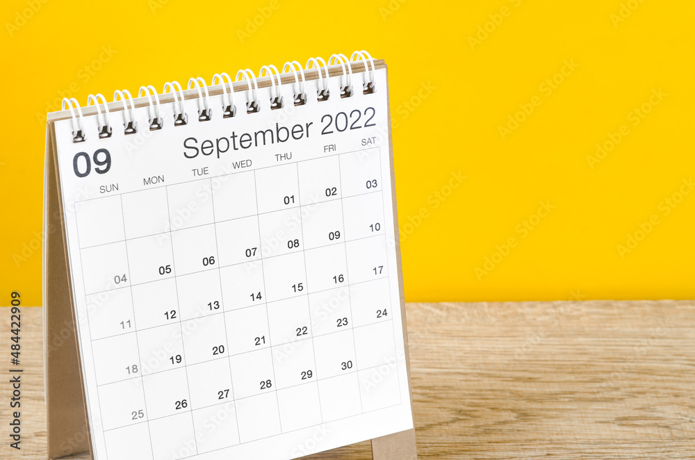 September 2022 desk calendar on wooden table with yellow background. - obrazy, fototapety, plakaty 