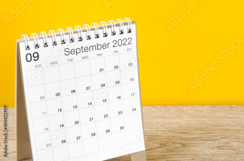 September 2022 desk calendar on wooden table with yellow background. photo