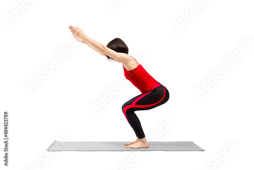 Yoga, chair pose. Attractive fit woman in red sportswear practice Utkatasana exercise, isolated on white.