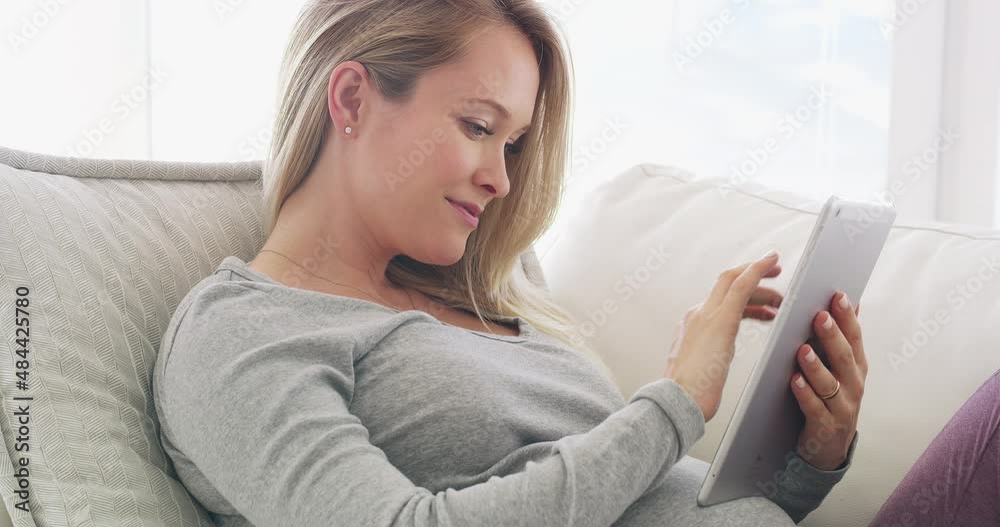 Learn everything about you and your baby with this app. Beautiful young pregnant woman relaxing on sofa at home, using a digital tablet to browse online. Expecting mother searching the internet, learn Learn everything about you and your baby with this app. Beautiful young pregnant woman relaxing on sofa at home, using a digital tablet to browse online. Expecting mother searching the internet, learn