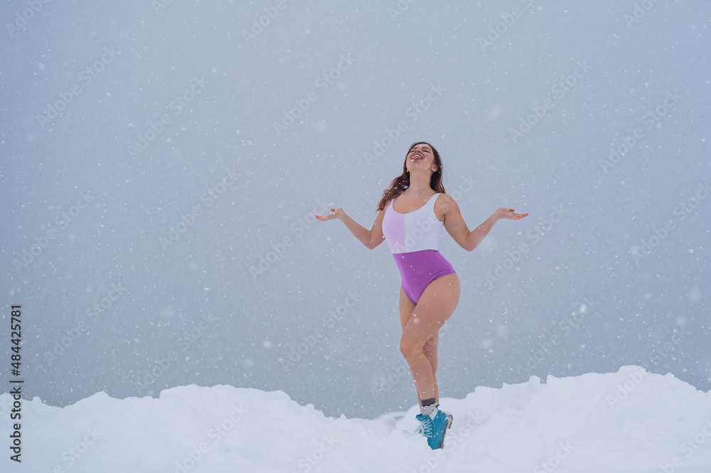 Happy woman in swimsuit catching falling snowflakes outdoors in winter. Cold therapy for immune support. Happy woman in swimsuit catching falling snowflakes outdoors in winter. Cold therapy for immune support.
