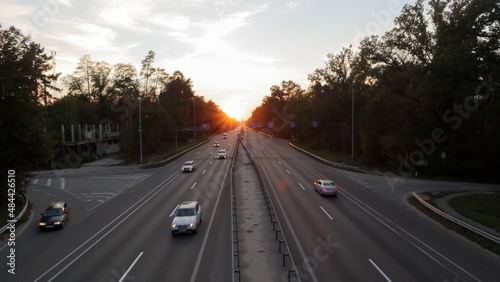 Moving cars on the motorway at sunset time. Highway traffic at sunset with cars. Busy traffic on the freeway, road top view. © Yevhen Roshchyn
