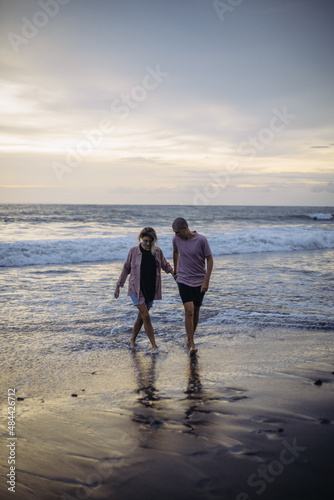 young beautiful couple in love walking at sunset by the ocean, couple relaxing in Bali, vacation in Bali, travel together, hug, love