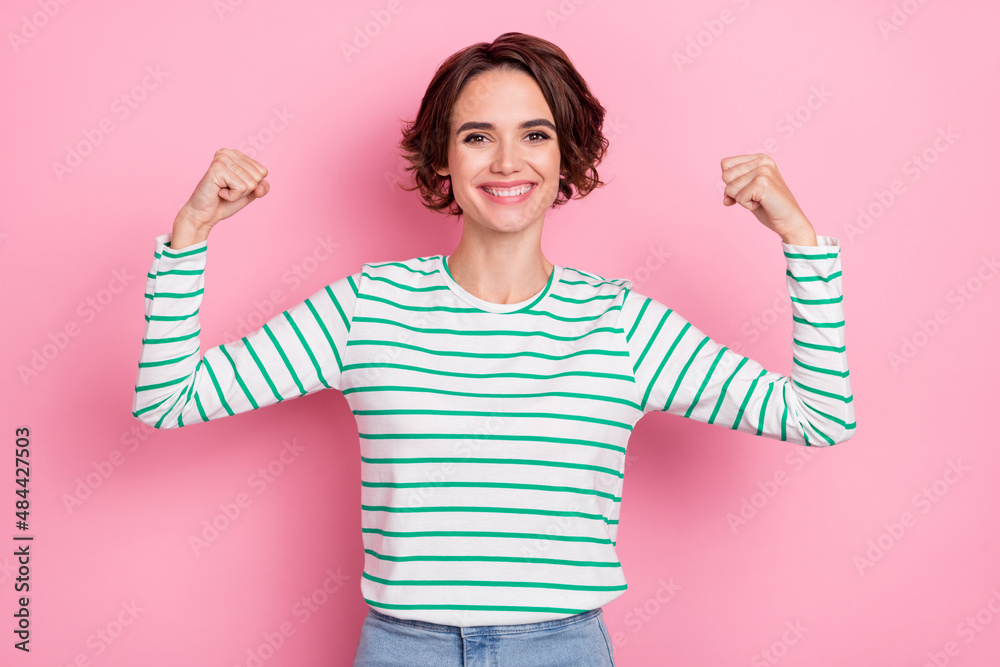 Portrait of attractive strong cheerful girl demonstrating biceps power isolated over pink pastel color background Portrait of attractive strong cheerful girl demonstrating biceps power isolated over pink pastel color background