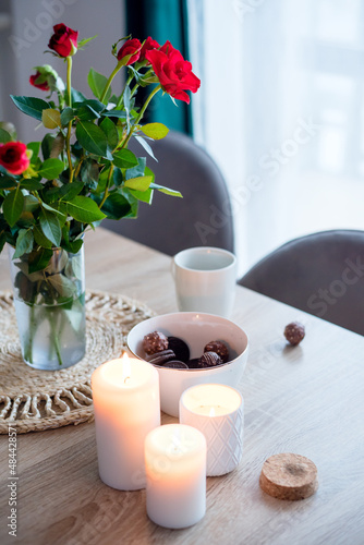 Coffee with sweets on the table  a vase with red roses and candles. Beautiful still life