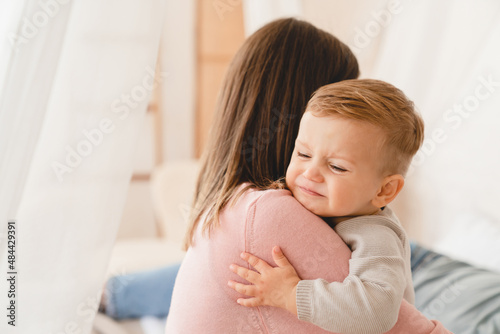 Caucasian mother lulling cradling her crying little small son daughter toddler infant newborn baby. Colics, teething health problems. Postnatal depression. Motherhood and childcare