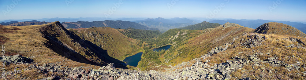 Panoramic photograph of a mountain landscape forming a rift in the mountain range, with two mountain lakes in the valley.