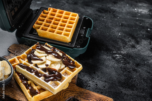 Breakfast with Belgian waffles, banana and Chocolate Syrup. Black background. Top view. Copy space