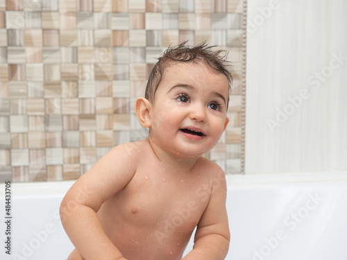 Portrait of a child bathing in the bathroom. Wide open brown eyes.
