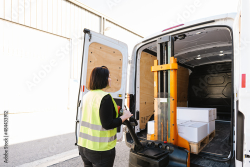 Anonymous woman loading boxes with stacker photo