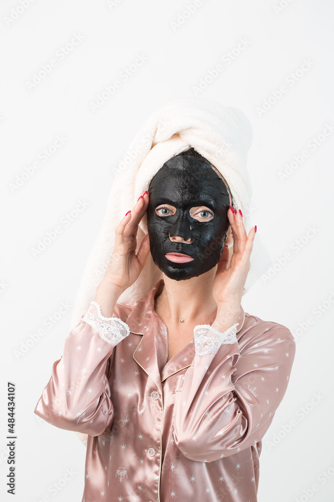 Face care and beauty treatments. Woman with a sheet moisturizing charcoal mask on her face isolated on white background