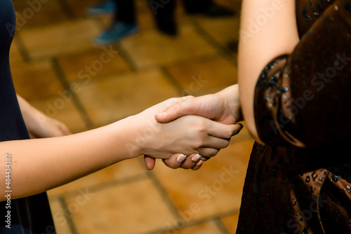 Two women with cute manicure shake each other's hands. A women's handshake. Event. Congratulations. Success. A handshake. Females. Manicure. Women. Gown. Dress. Solemn atmosphere