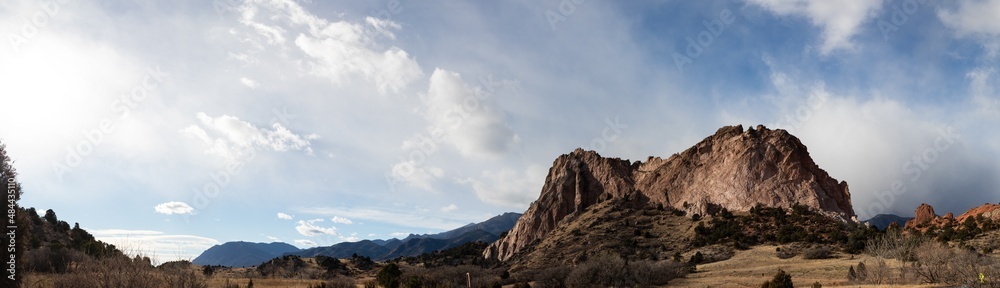 Panorama of a massive rock outcropping before a ridge of the Rocky Mountains, Colorado American west with dramatic clouds, horizontal aspect Panorama of a massive rock outcropping before a ridge of the Rocky Mountains, Colorado American west with dramatic clouds, horizontal aspect