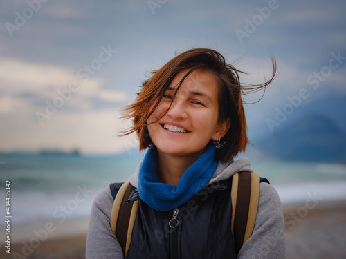 antalya, turkey, winter walk by the mediterranean sea. Attractive young woman standing on a windy cold beach. © YURII Seleznov