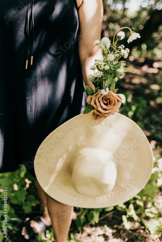 Close up of woman holding freshly picked flowers and large sun hat