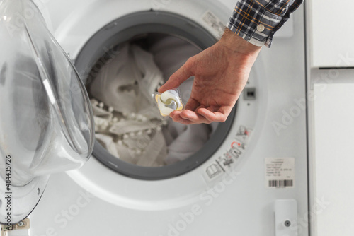 Gel caps in hand for washing machine, liquid coloured detergent and conditioner photo