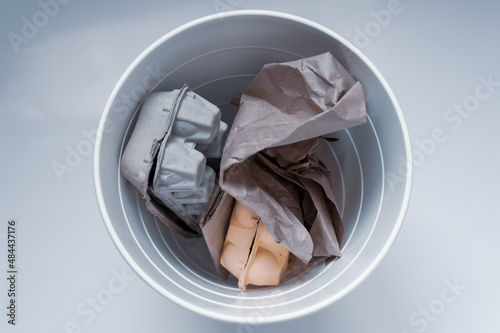 Paper garbage in a white trash can on a white background