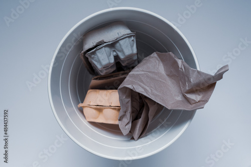 Paper garbage in a white trash can on a white background