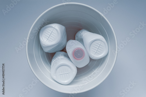 White plastic bottles in a trash can on a white background